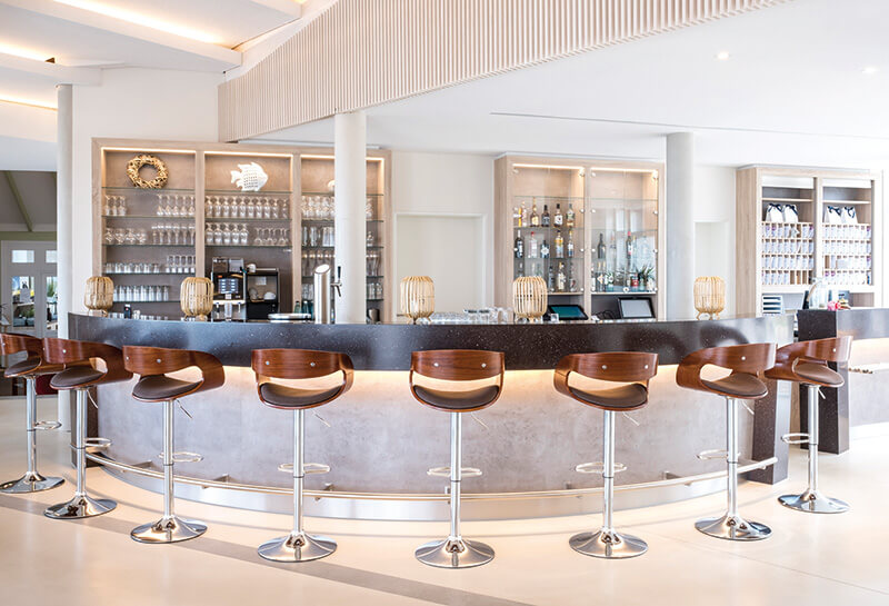 Beleuchtete Bar mit acht Holzhockern